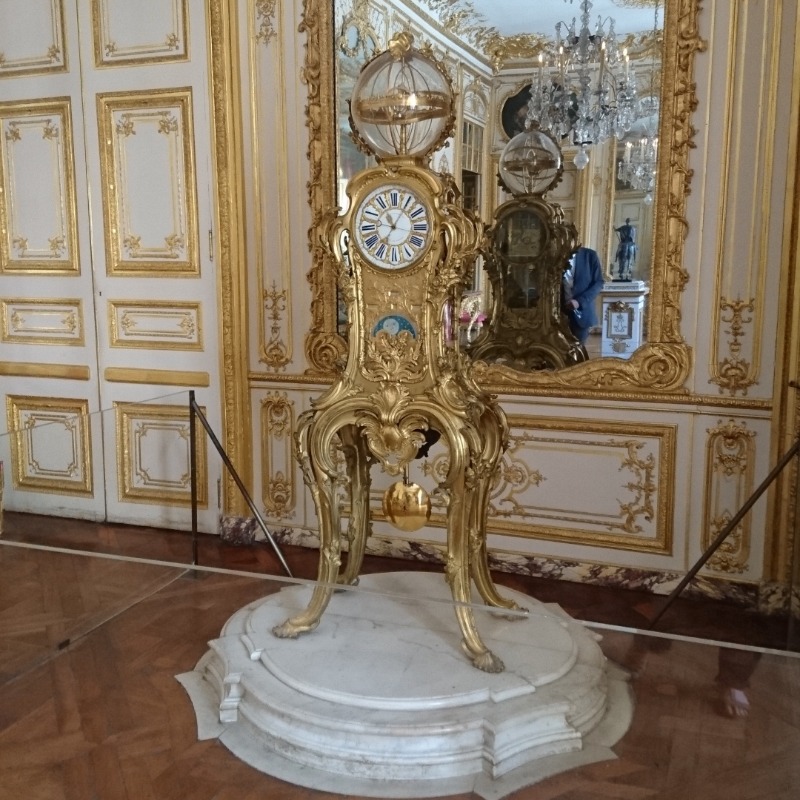 Eine Standuhr aus Gold mit einer Weltkugel als Abschluss oben.