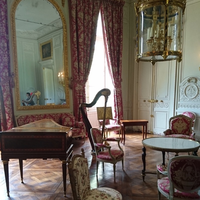 Im Petit Trianon: rosa Vorhänge und Polster. Eine Harfe und ein Klavier sind zum Spielen bereit.