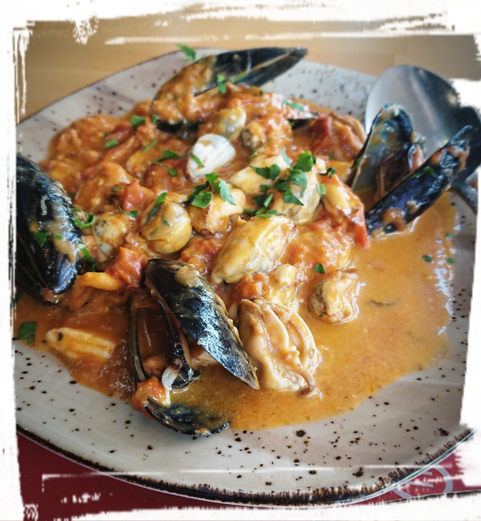 Meeresfrüchte in gelber Soße und mit Feta überbacken.