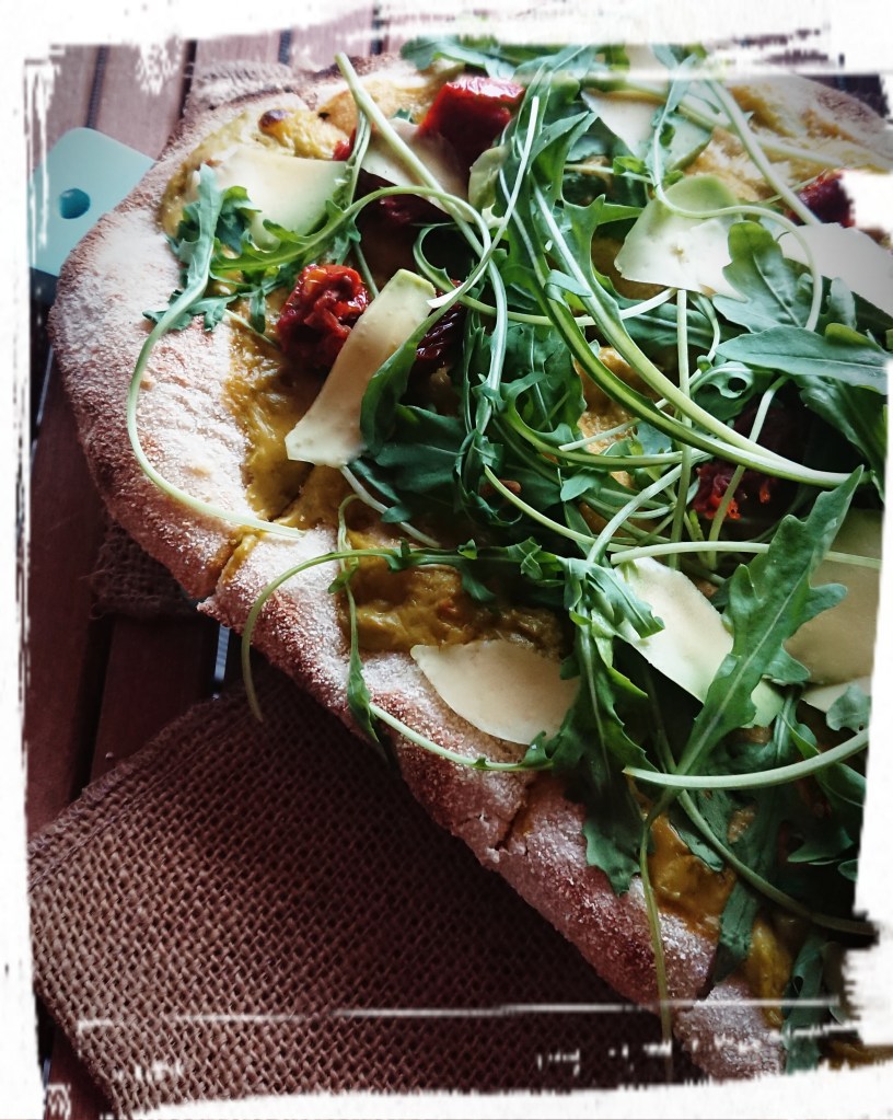 Vegetarische Pinsa mit Avocado und Ruccola belegt.