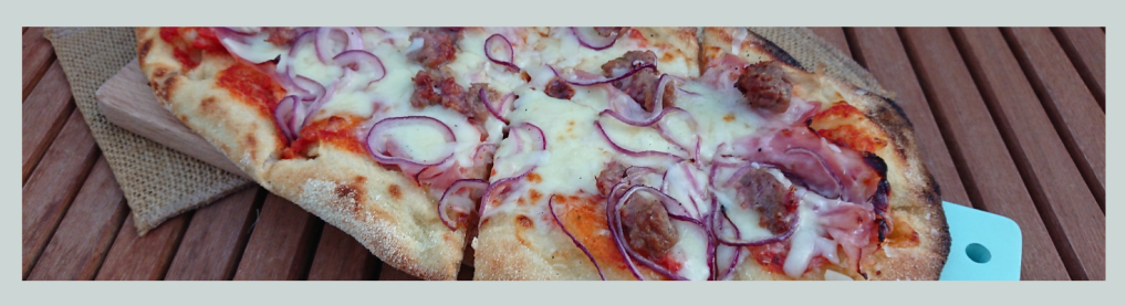 Pinsa ist eine längliche Pizza. Belag mit Schinken, Zwiebeln und Käse