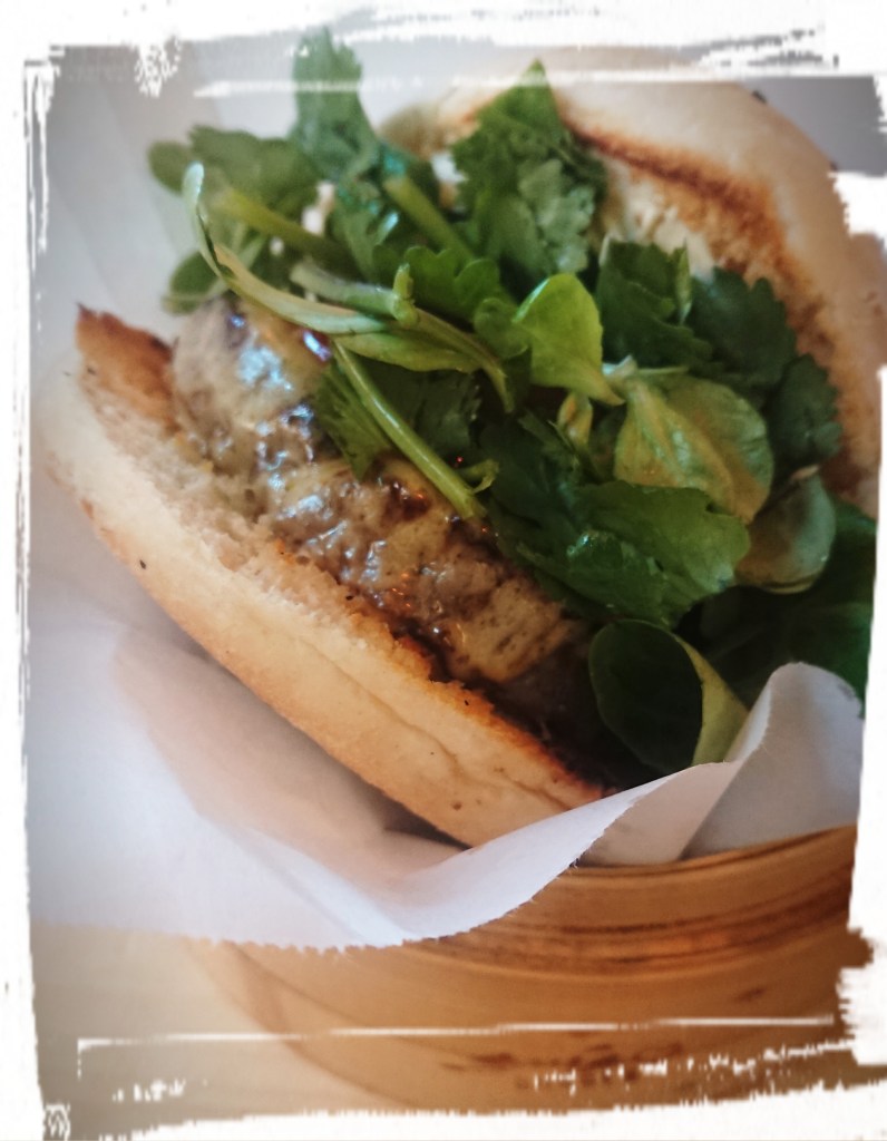 Ein Burger im hellen Bun mit Fleisch, Käse und viel Salat.