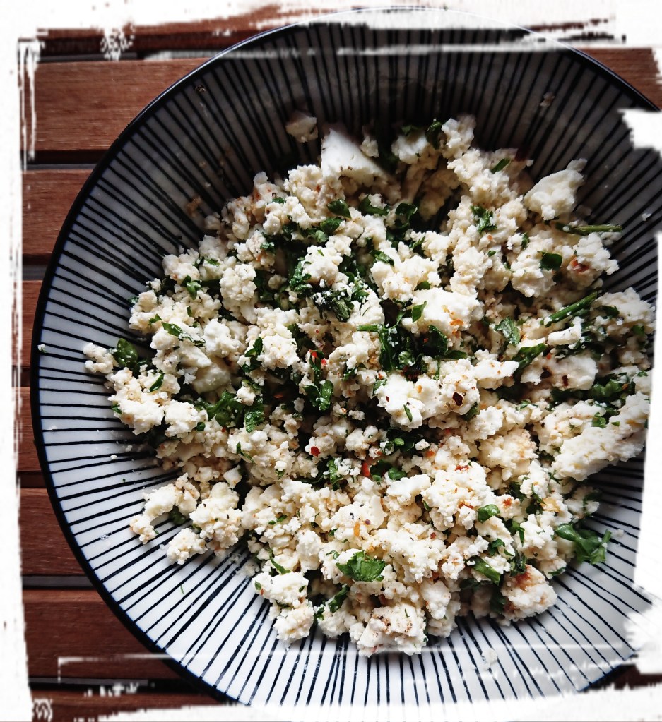 In Stückchen gebröselter Feta mit grünen Kräutern vermischt.