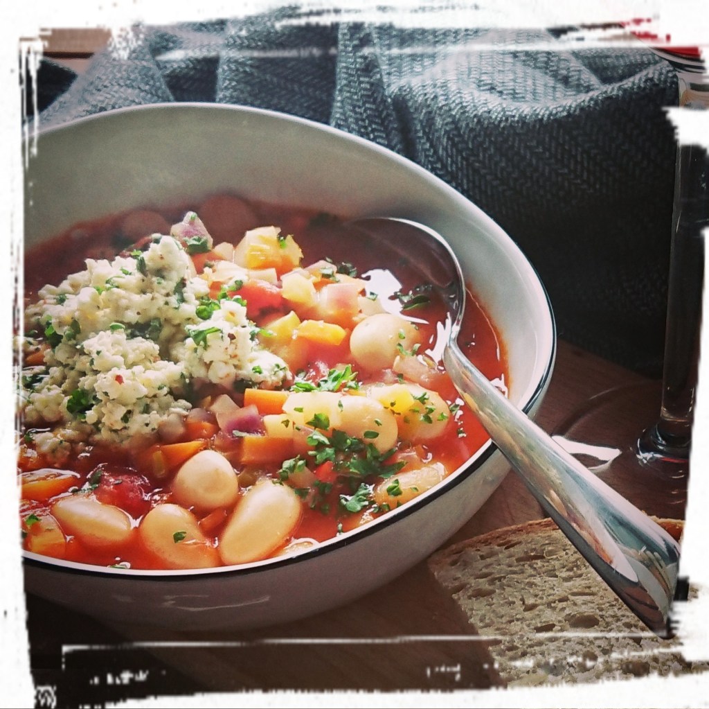 Die fertige Fasolada hat eine knallrote Farbe, die weißen Bohnen und das Topping aus Schafskäse runden sie ab.