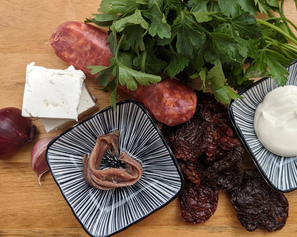 Feta, Sardellen, Salsiccia, getrocknete Tomaten, Petersilie und Crème fraîche sind die Zutaten für das Pasta-Gericht.