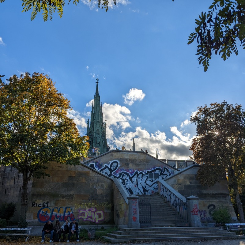 Blick auf das Nationaldenkmal mit dem spitzen, gotischen Türmchen. Blauer Himmel und Herbstlaub.